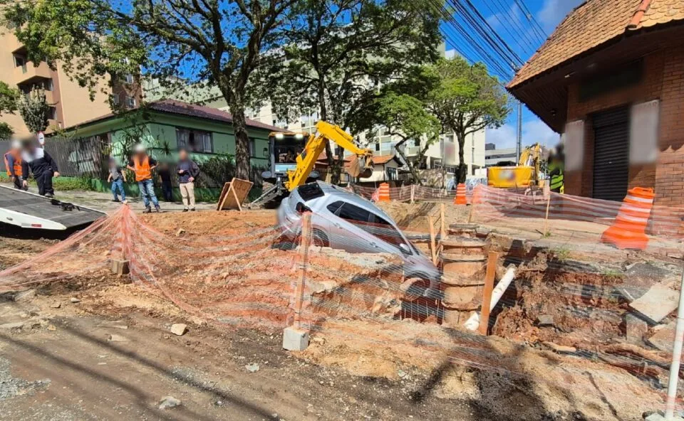 Susto! Carro com três estudantes cai em cratera de canteiro de obras no Mercês, em Curitiba; veja vídeo