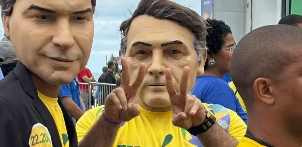 Apoiadores usam máscaras de Jair e Flávio Bolsonaro em ato de campanha