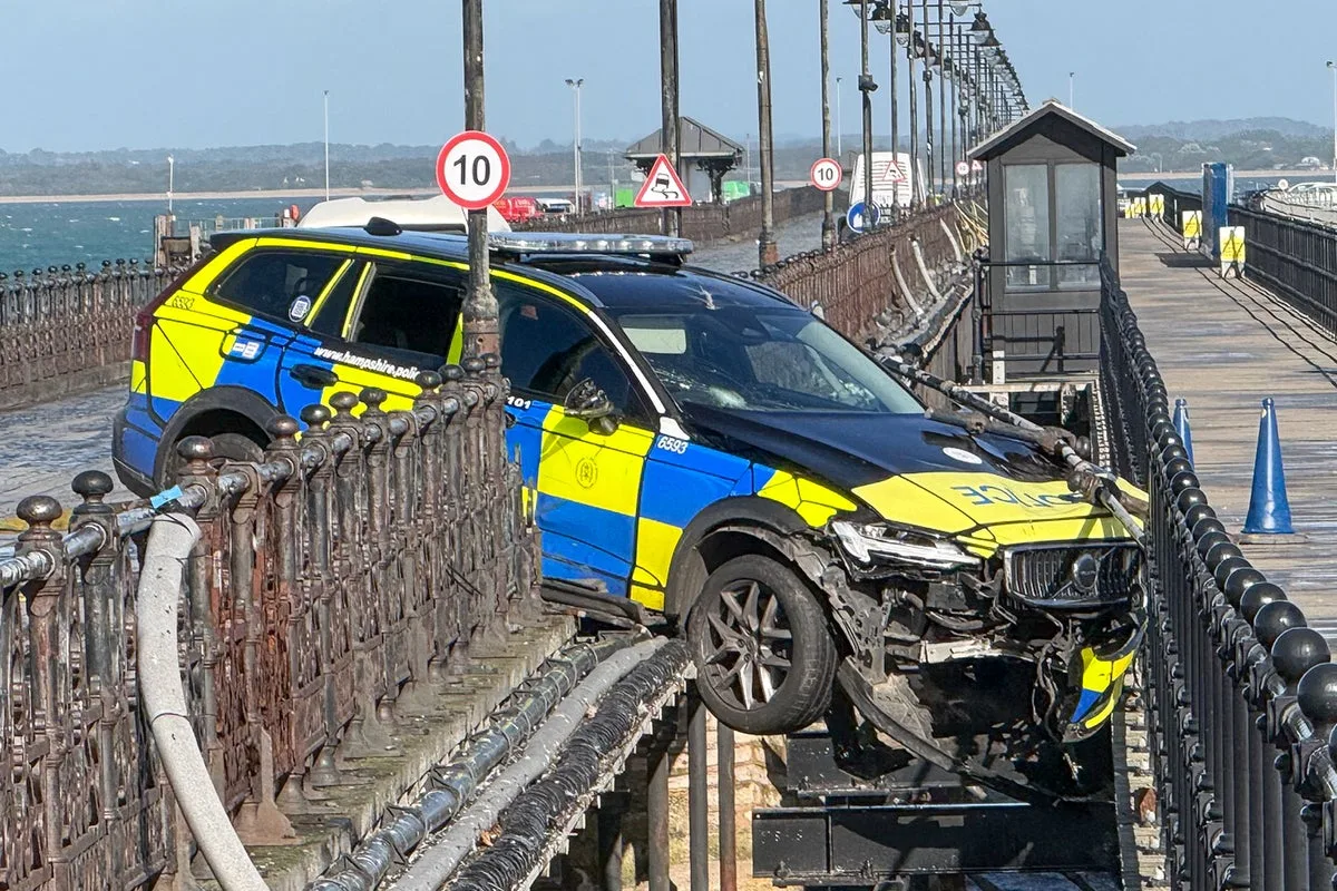 Police car left dangling mid-air after crashing through railings on pier