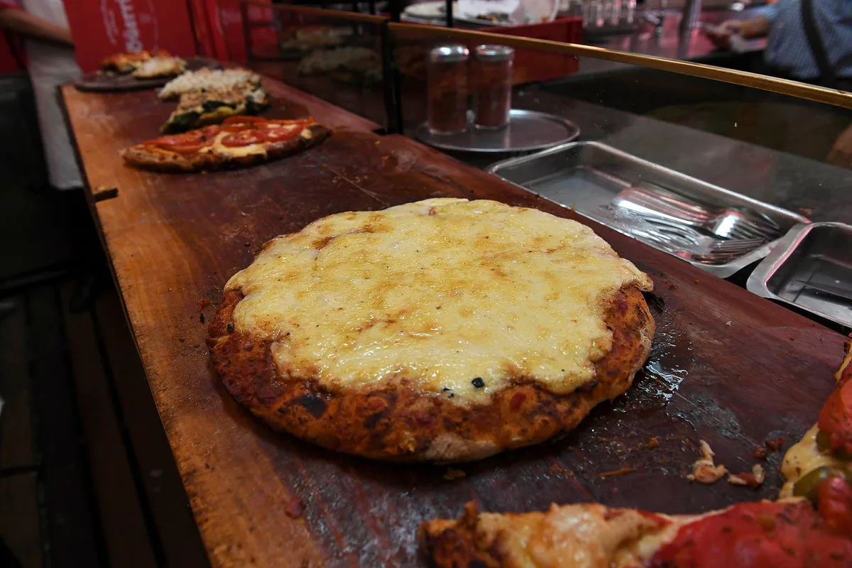 Fue a una emblemática pizzería porteña, pidió una pizza de muzzarella chica, faina y cerveza: el ticket se viralizó