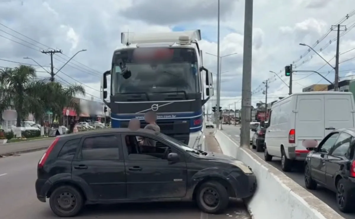 Carro entra em ponto cego de caminhão, é arrastado e bate contra mureta em Pinhais