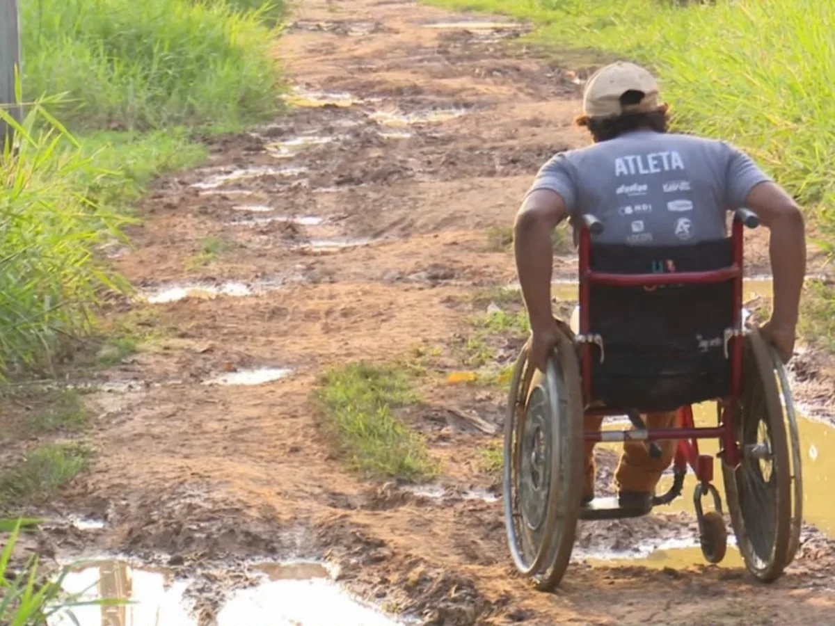 VÍDEO: Cadeirante atravessa rua com lama e buracos para poder chegar em via pavimentada no Acre