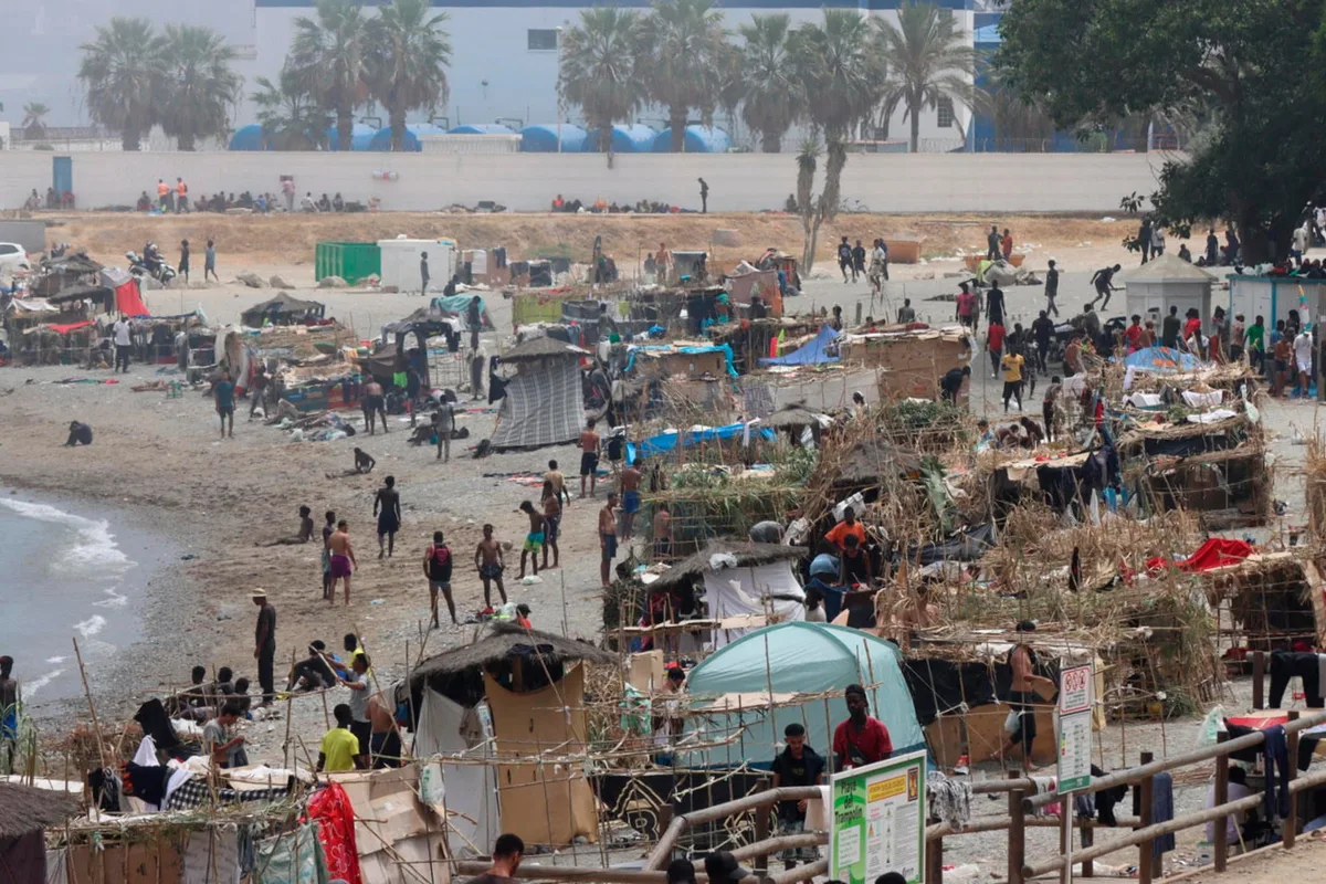 Cientos de migrantes levantan chozas improvisadas con cañas, plásticos y cartones en la playa del Trampolín de Ceuta mientras esperan una solución a su situación